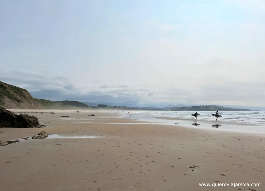 Dos surfistas entran al agua en la extensa playa de Merón